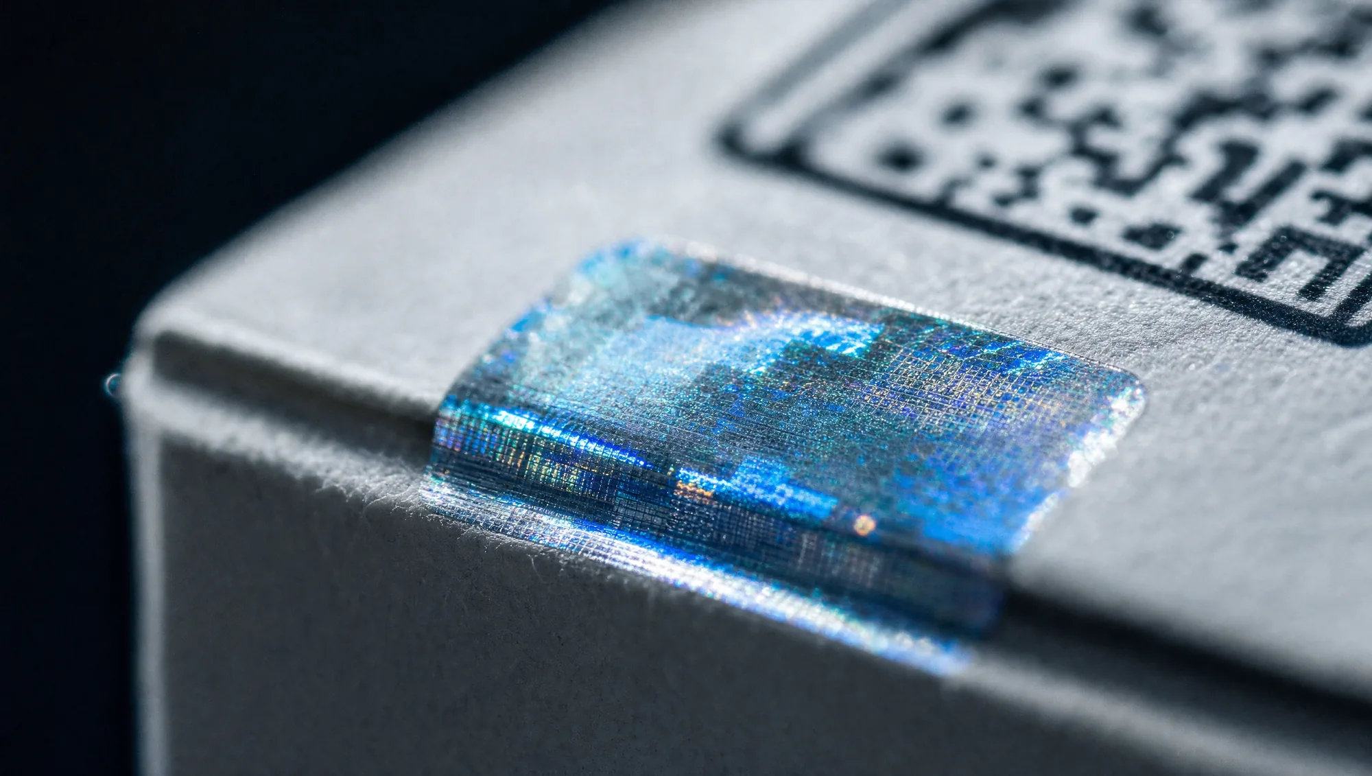 Detalle macro de holograma de seguridad y código QR sobre el empaque